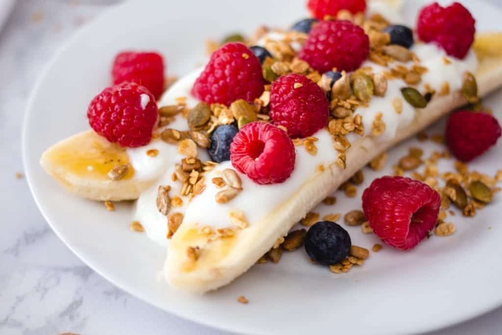 Banana with yogurt, granola and berries close up 