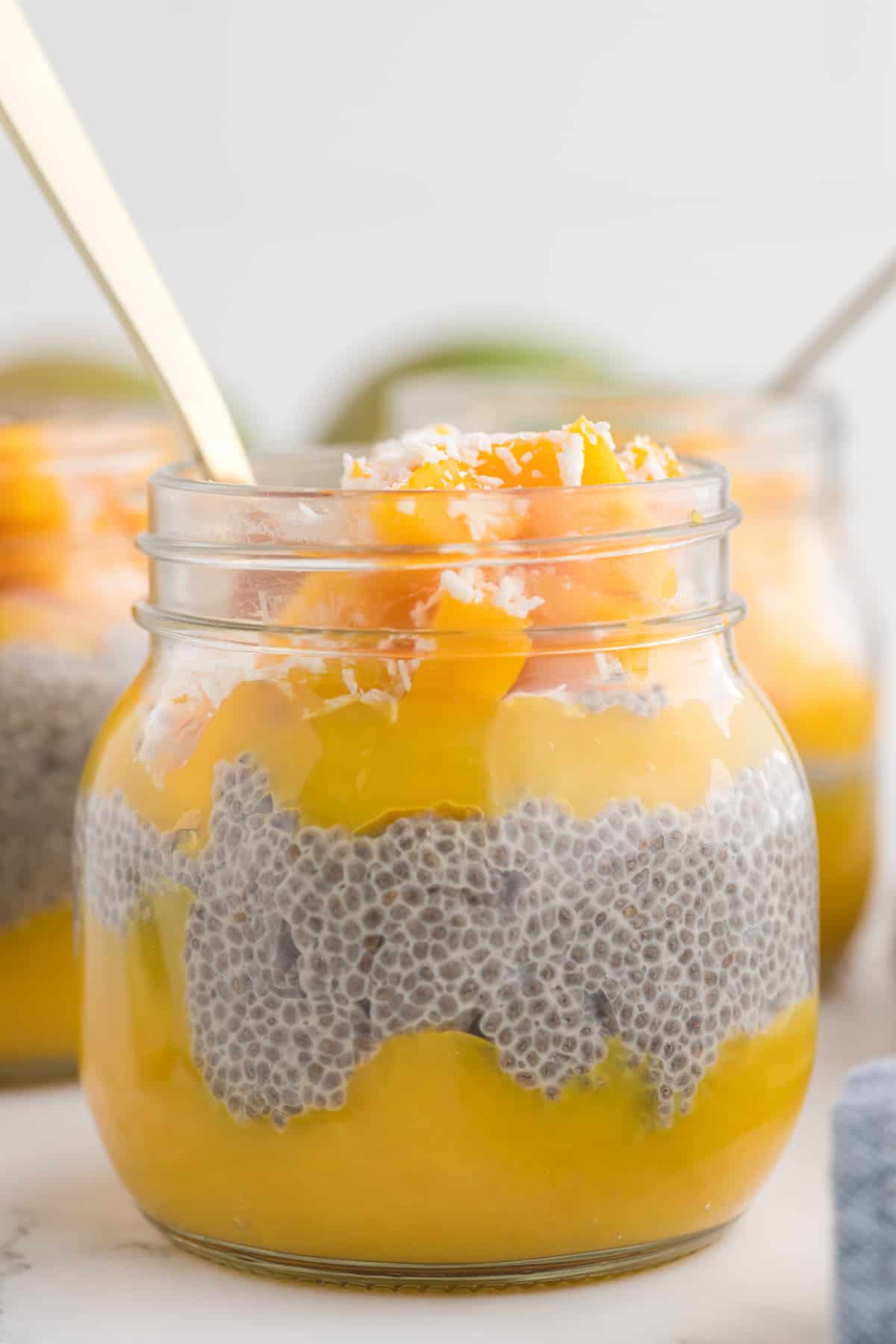 mango chia pudding in a jar with a spoon.