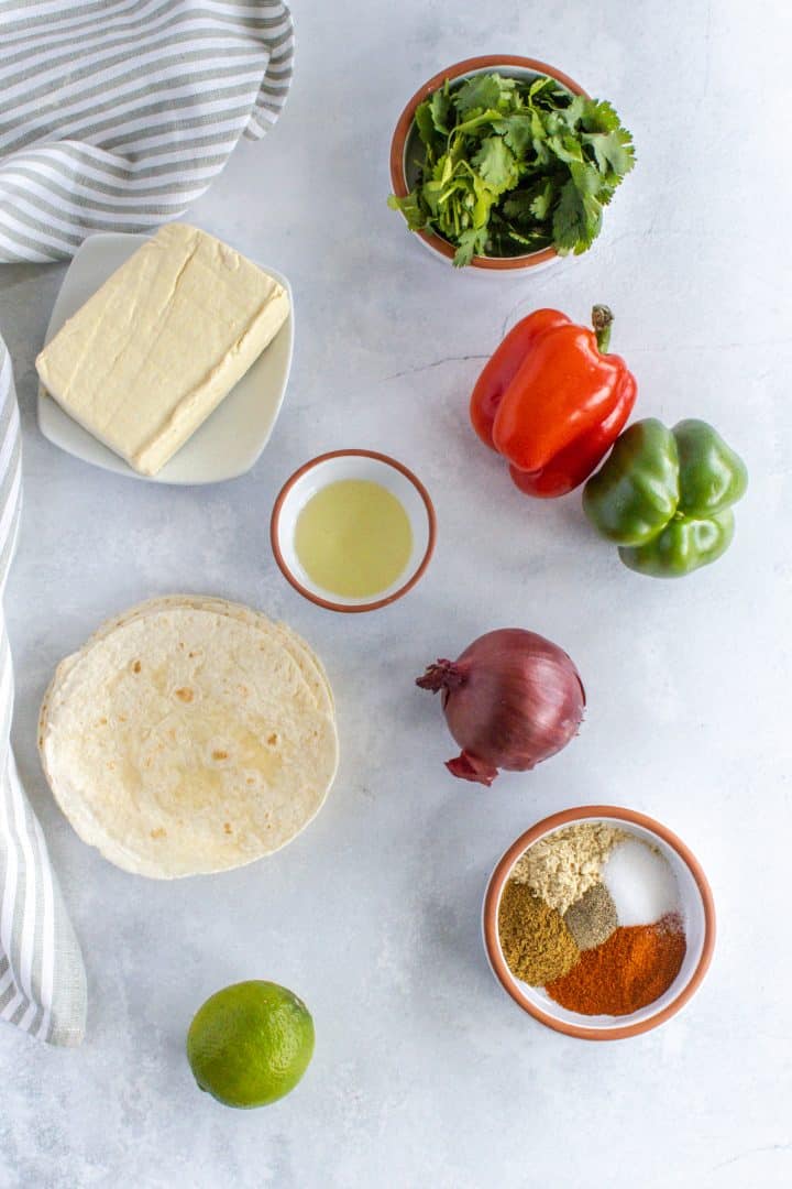 all the ingredients needed to make the tofu fajitas, tofu, tortillas, spices, onion, pepper, coriander