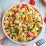 Pasta salad in a serving bowl with cherry tomatoes on the side.
