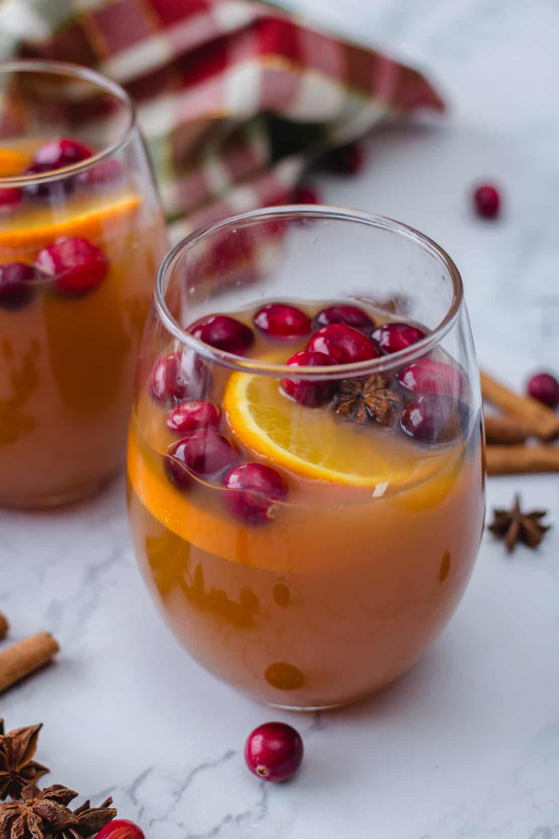 Apple Cider and pear cider in in a glass with cranberries on top