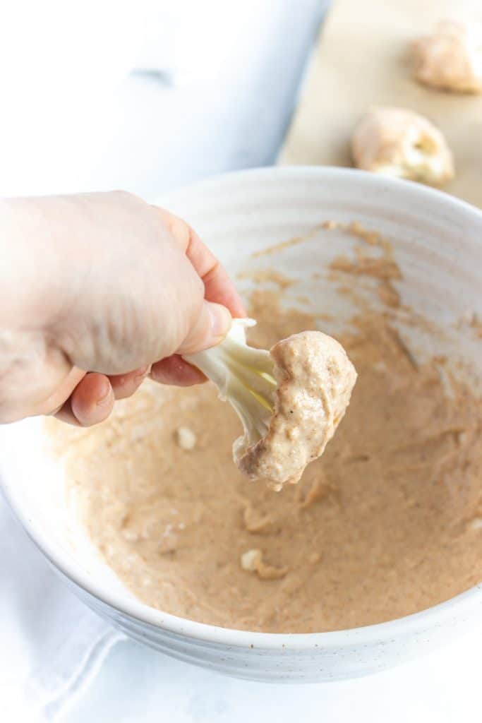 dipping the cauliflower floret in the flour mixture