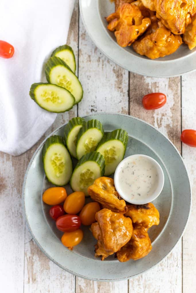 Cauliflower wings in a plate with slices cucumber and cherry tomatoes 