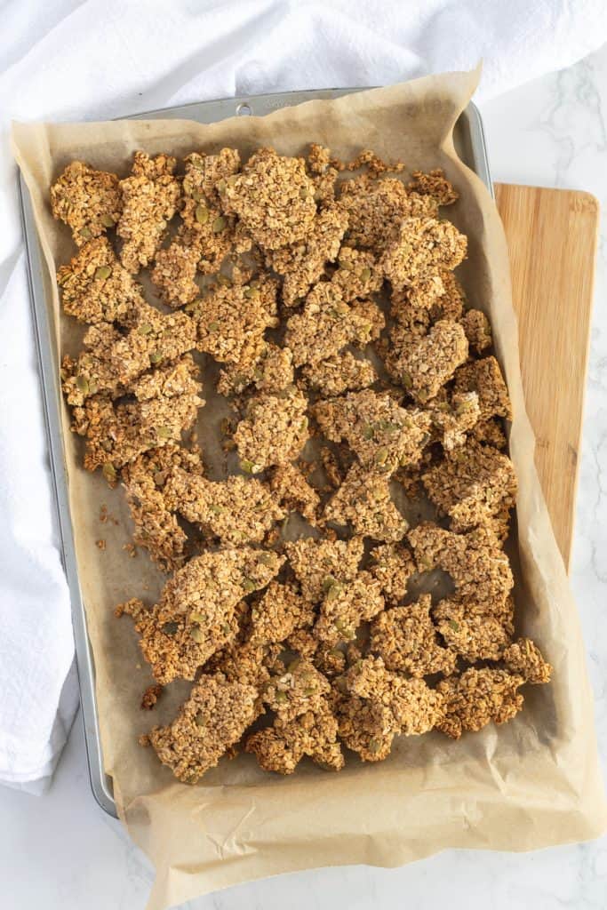 Sheet pan with cooked granola clusters in pieces