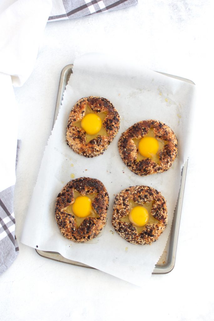 bagel on a sheet pan with uncooked inside inside the hole