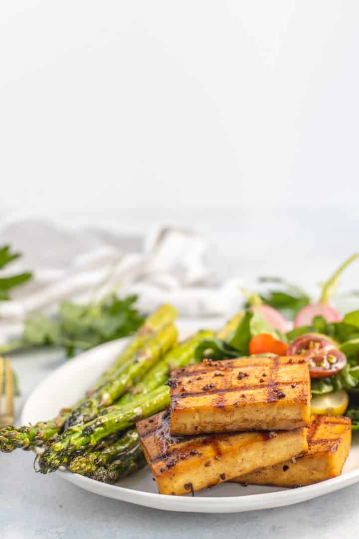 Marinated balsamic tofu in a plate with asparagus and salad