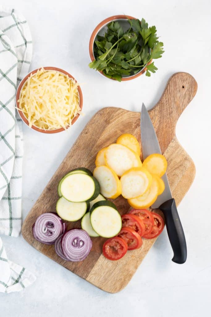 zucchini and summer squash sliced on a wooden board.