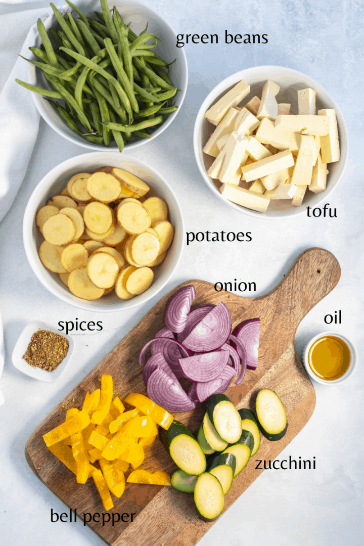 all the ingredients you need to make the recipe: green bean, tofu, potatoes, spices, onion, oil, zucchini, bell pepper.