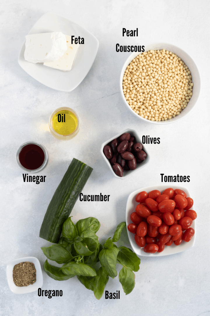 All the Ingredients you need to make this recipe: Pearl couscous, Feta, Oil, Vinegar, olives, cucumbers, tomatoes, oregano, basil.