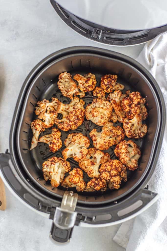 Cauliflower florets in the basket of the air fryer reading to be cook