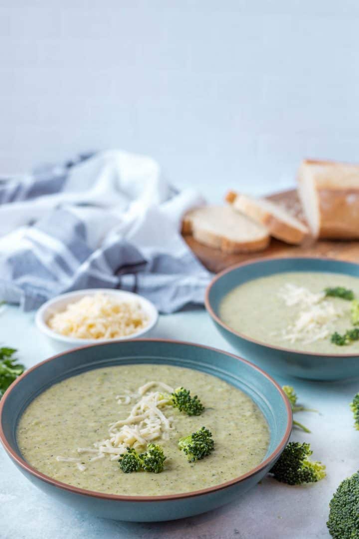 Healthy broccoli Cheddar Soup serve in 2 bowls with bread in the background