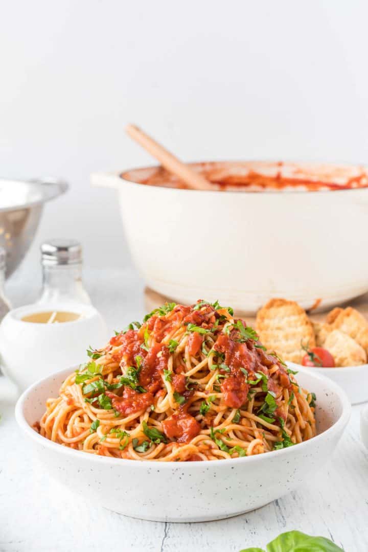 Vegan Red Lentil Bolognese in a white bowl with bread in the background