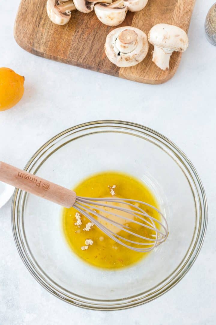 Bol avec huile d'olive, just de citron et poudre d'ail prêt être mélangé.