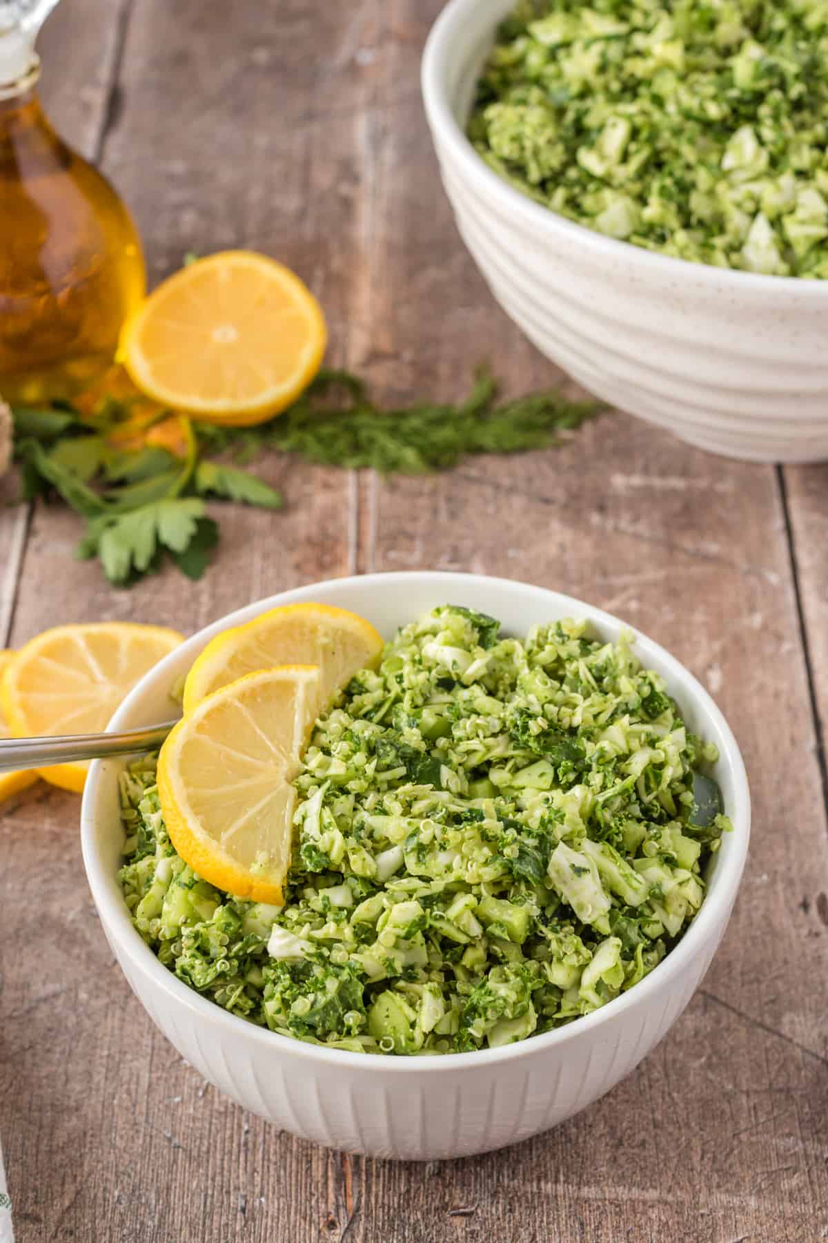 Green goddess salad in a white bowl with lemon slices