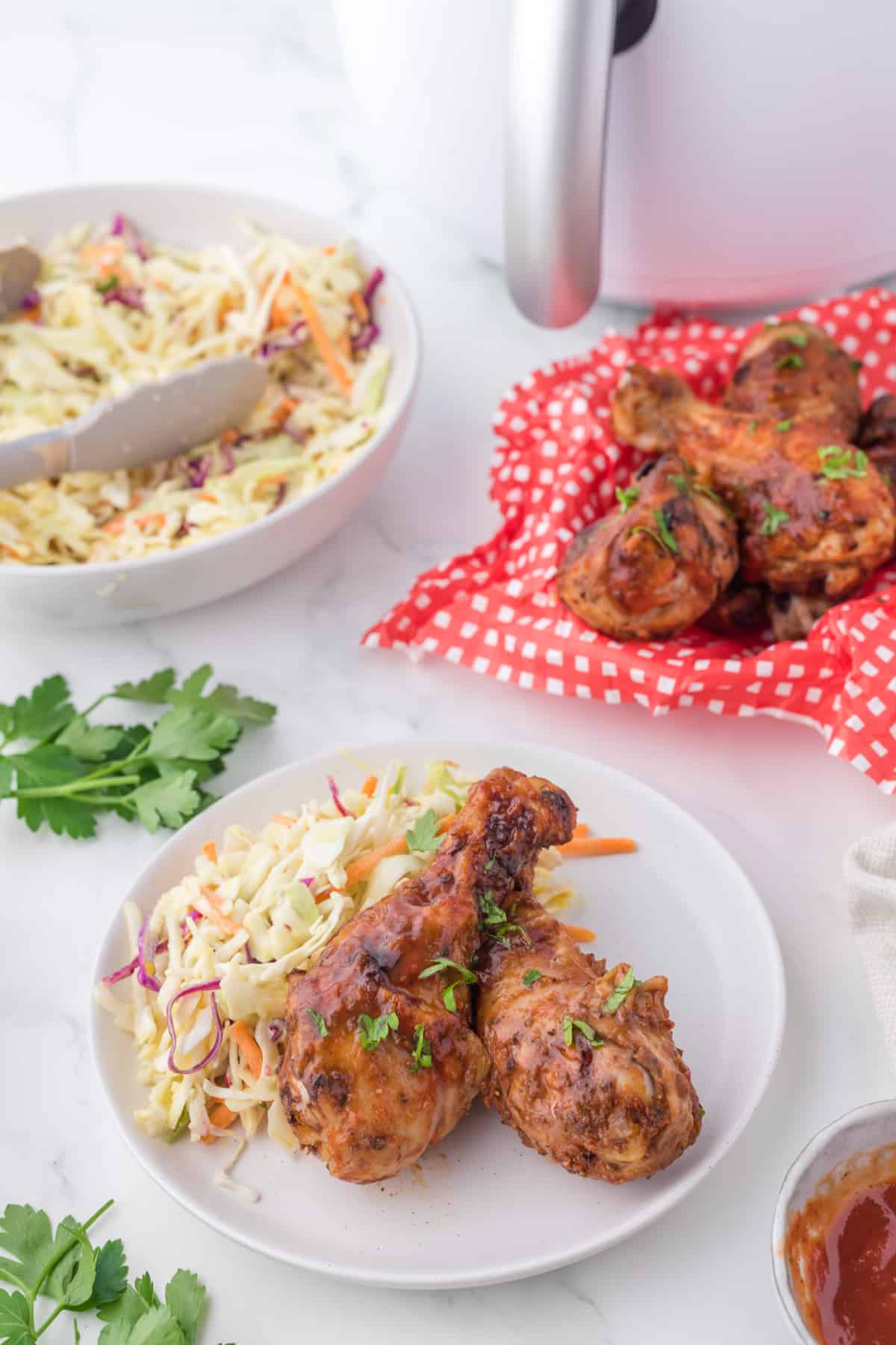 cooked chicken drumsticks on a white plate with coleslaw on the side.