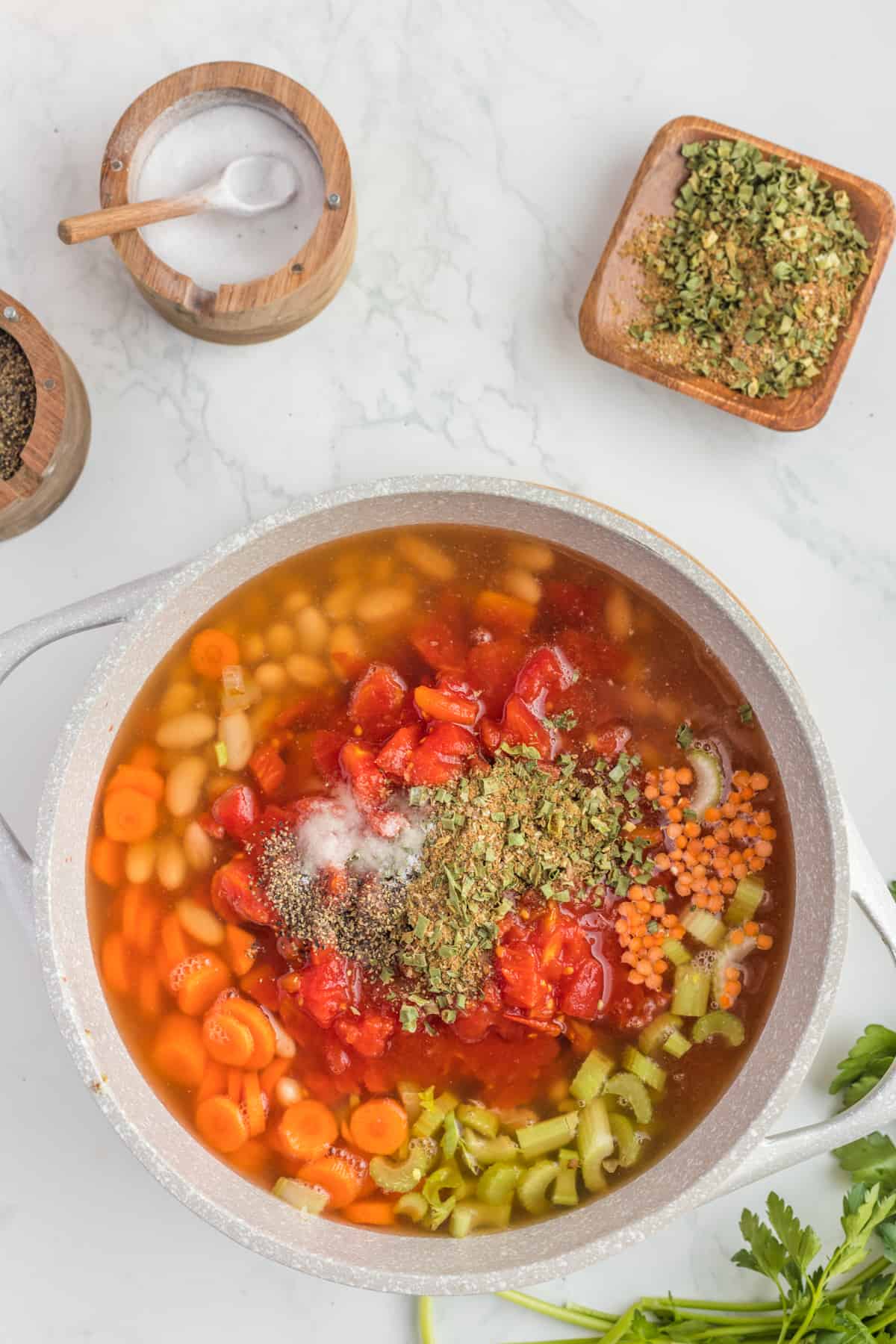 adding the broth and spices to the soup.