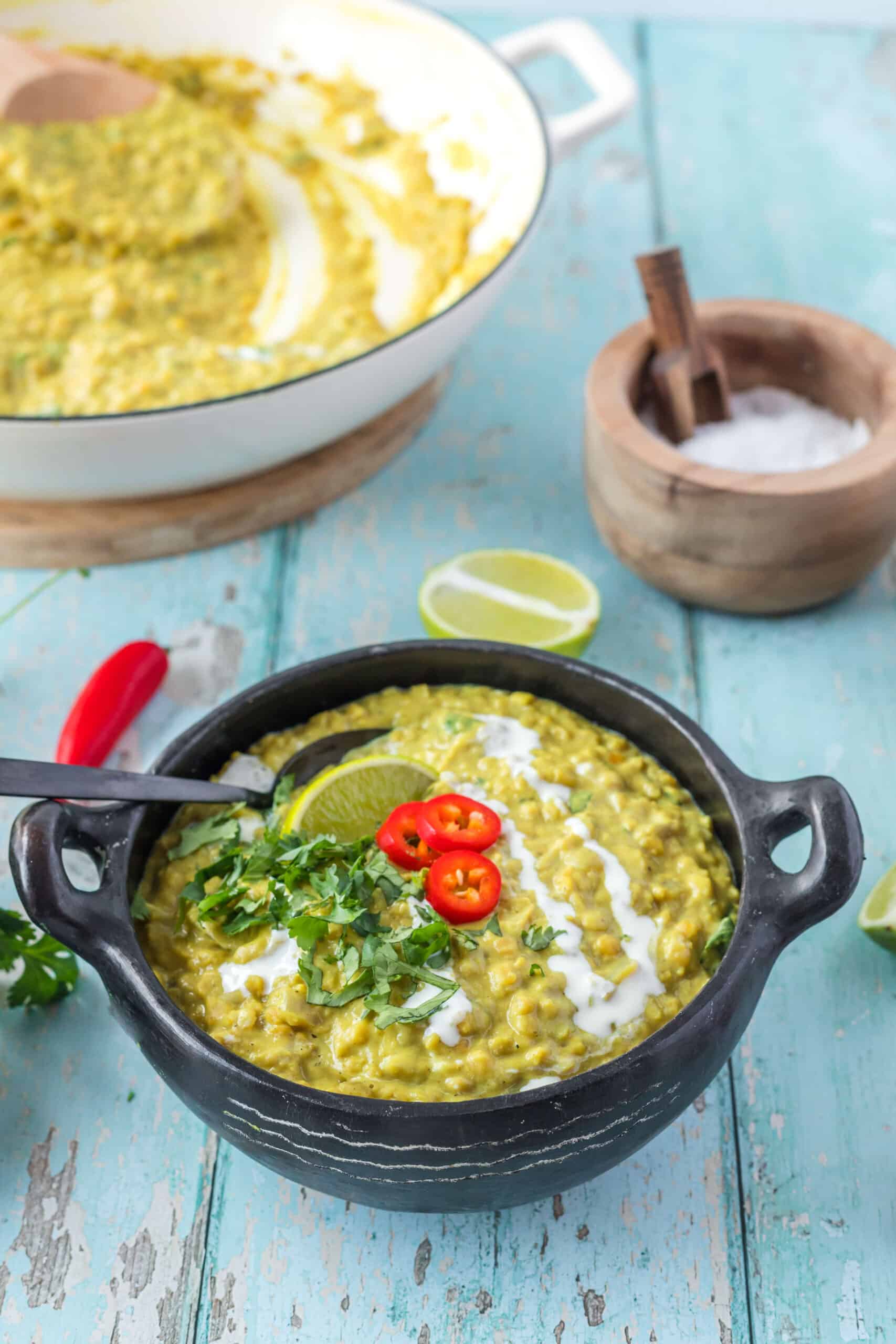 Dahl serve in a bowl with lime,cilantro and slices of red hot pepper on top.