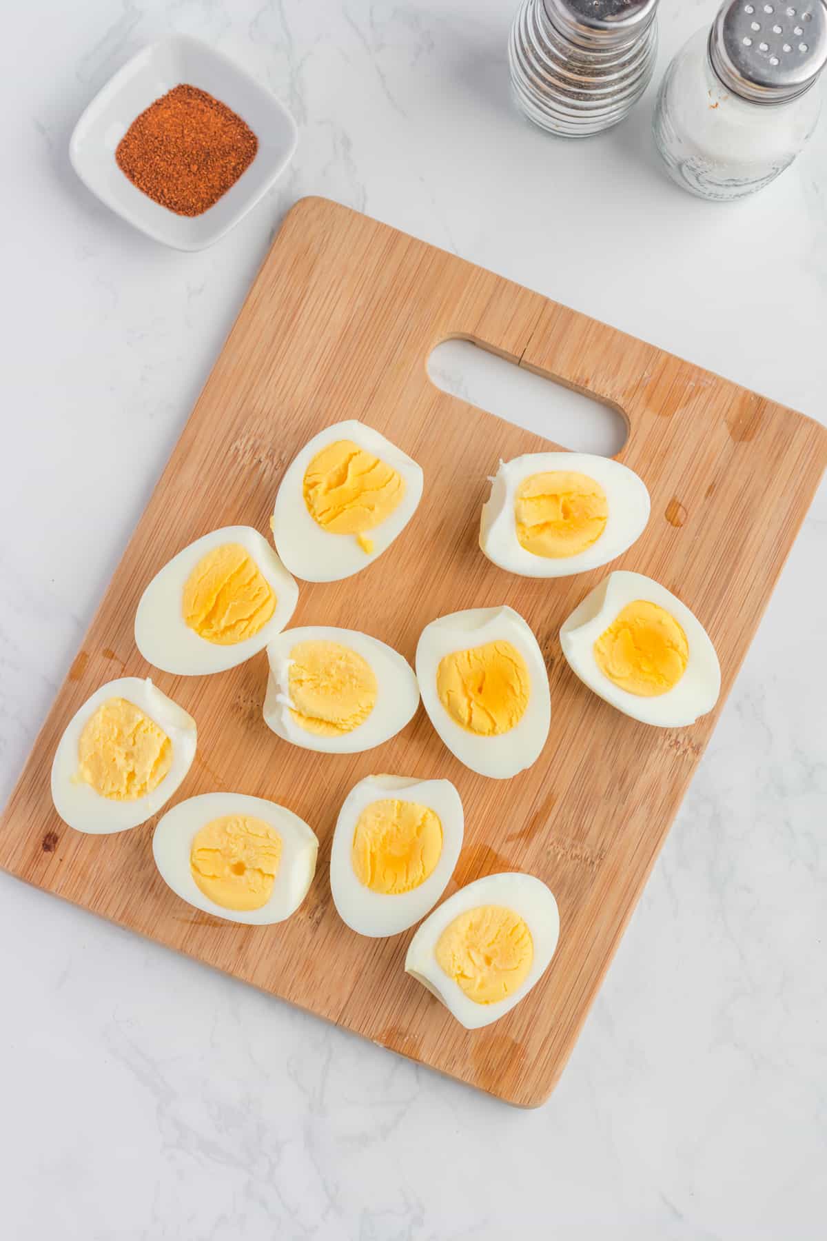 Boiled eggs cut in half on a wooden board.