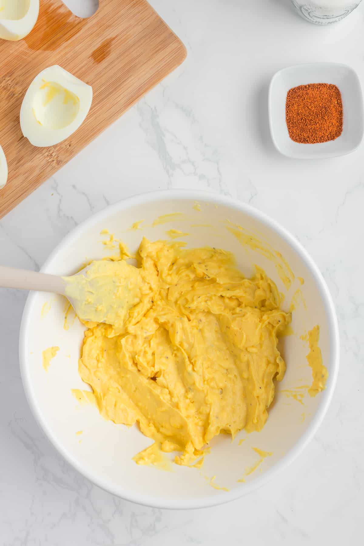 yolk mixture in a white bowl with a spatula.