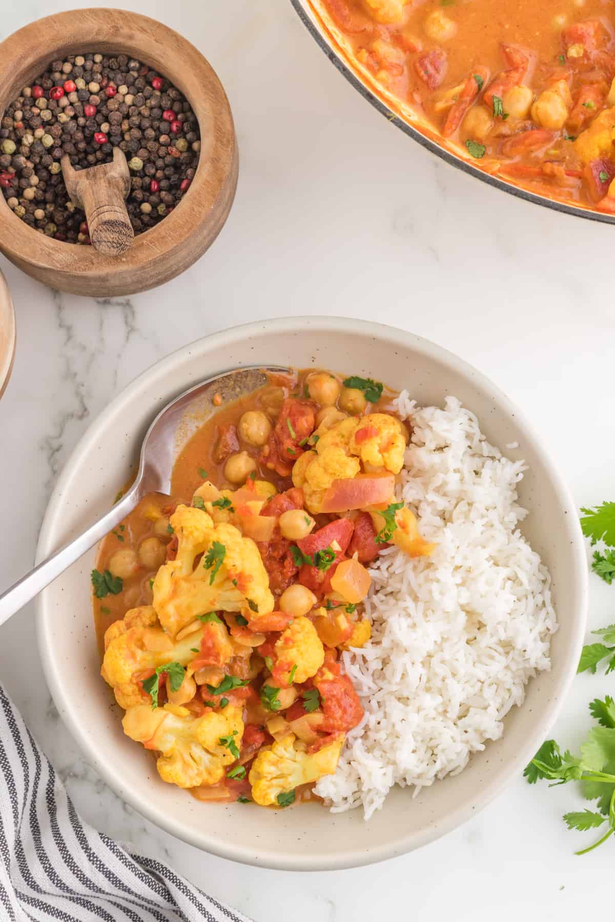 Cauliflower Chickpea Curry serves in a bowl with a spoon top view.