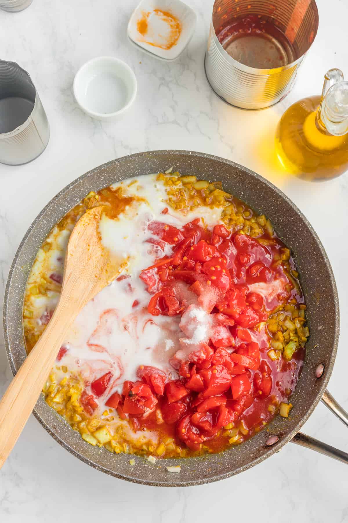 Adding coconut milk and tomatoes to the saucepan