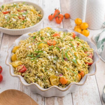 Orzo Pesto Salad in a serving bowl, with grapes tomatoes on the side.