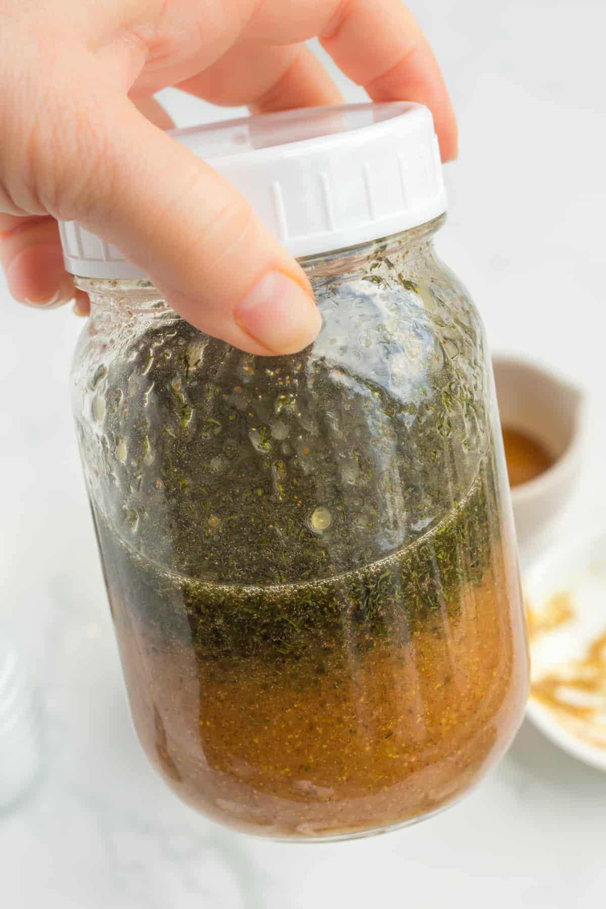 hand holding the dressing in a mason jar. 