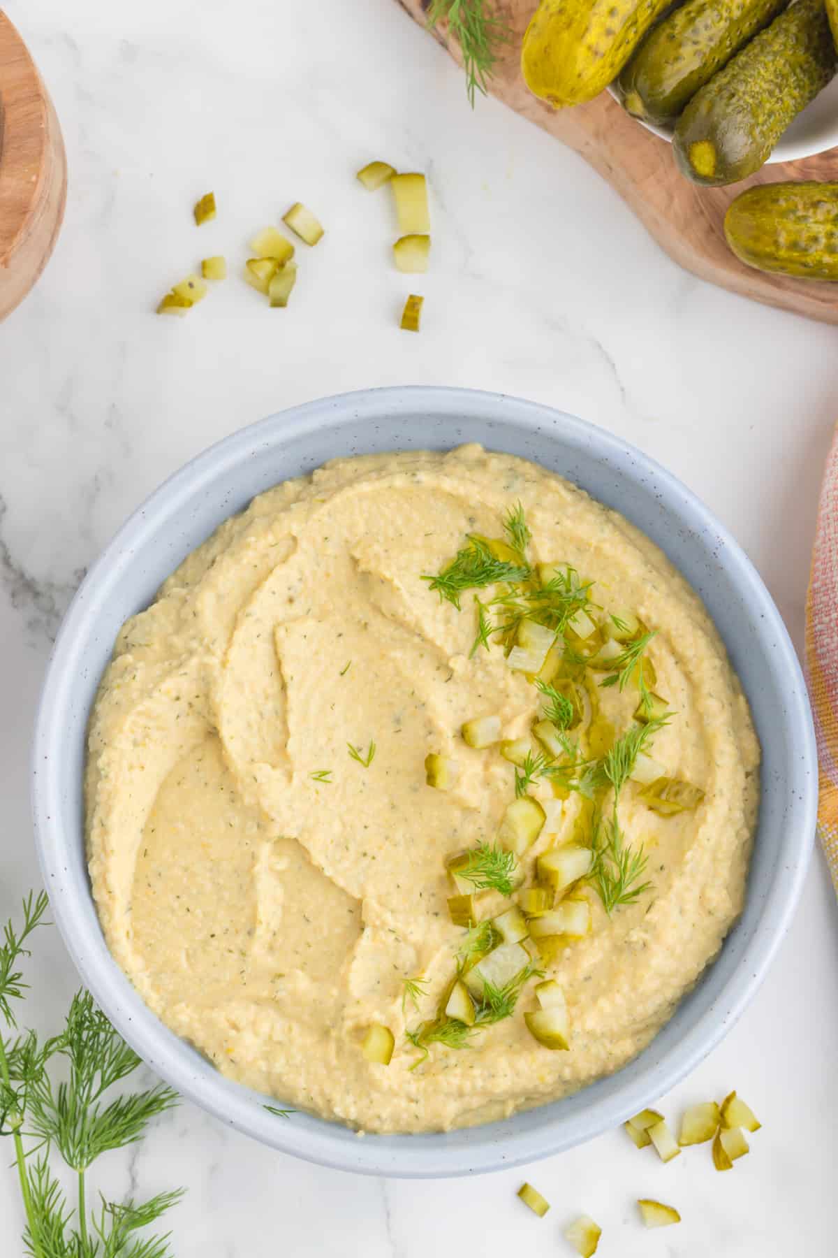 dill pickle hummus serve in a blue bowl, top view