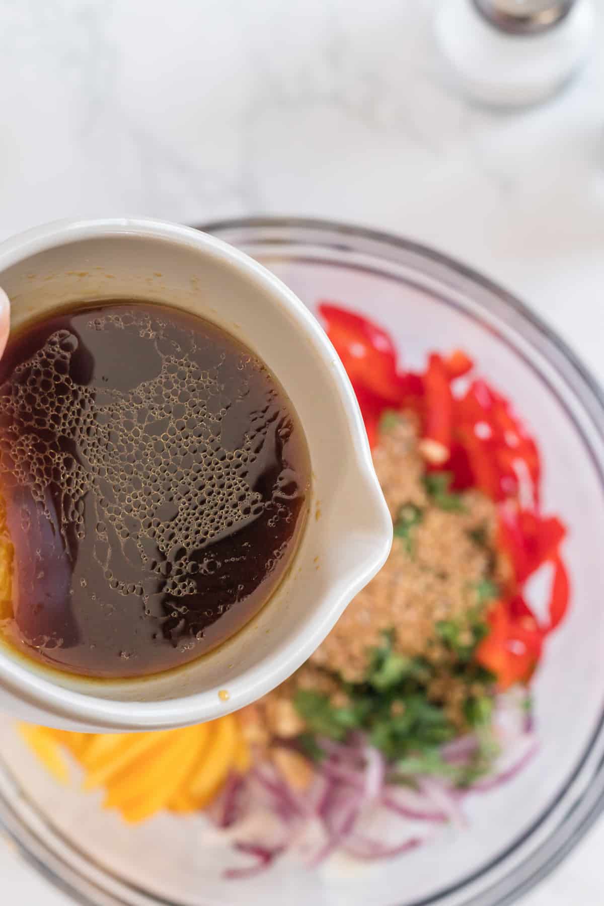 pouring the dressing over the salad.