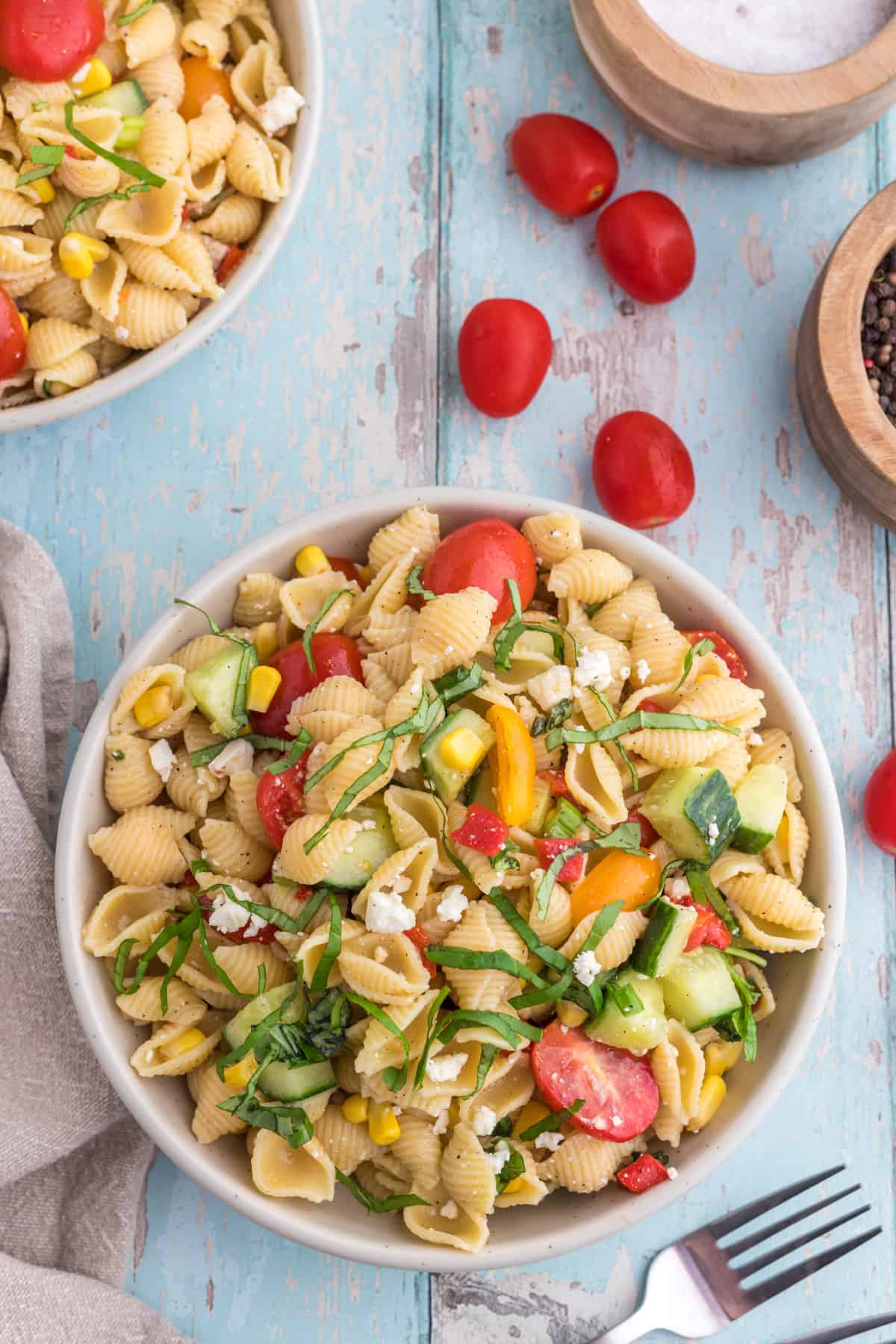 Pasta salad in a serving bowl with cherry tomatoes on the side.