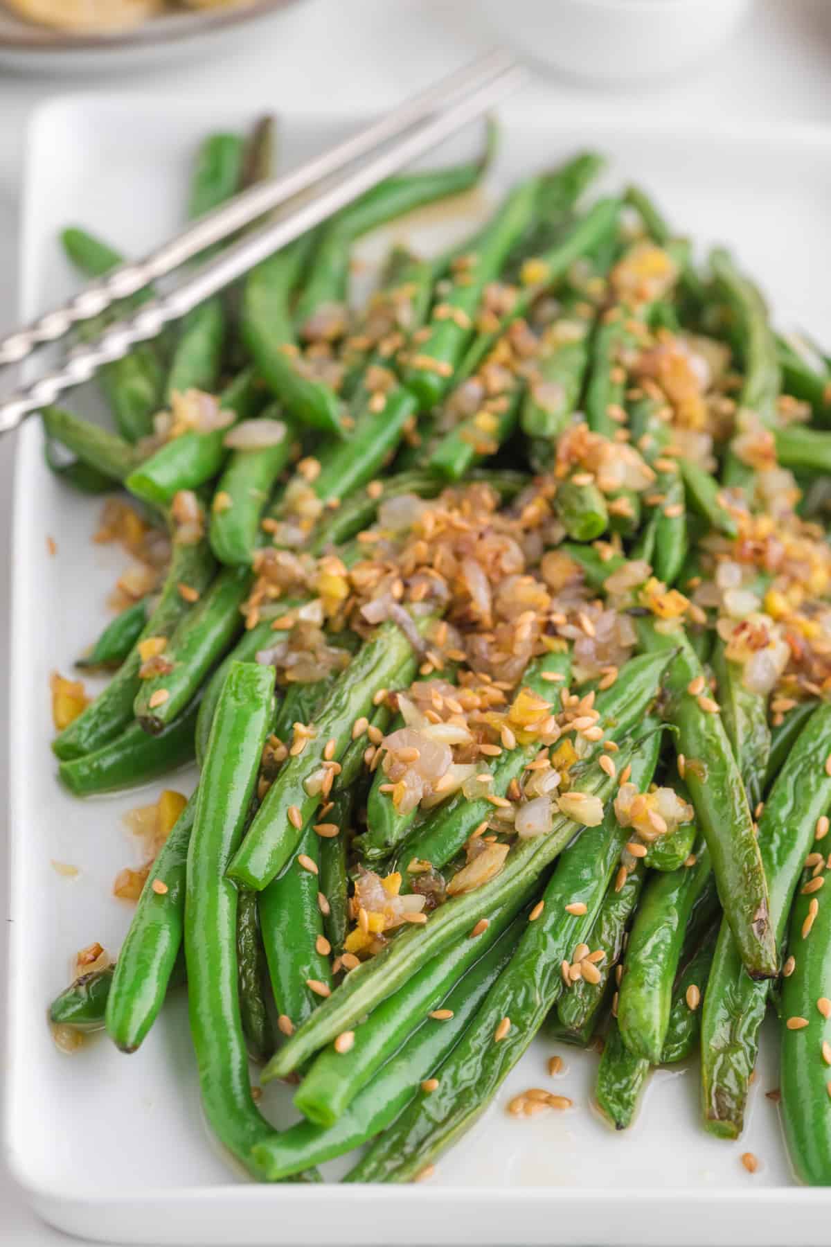 Easy Chinese Green Beans (Din Tai Fung Style) serve in a white serving plate with chopsticks.