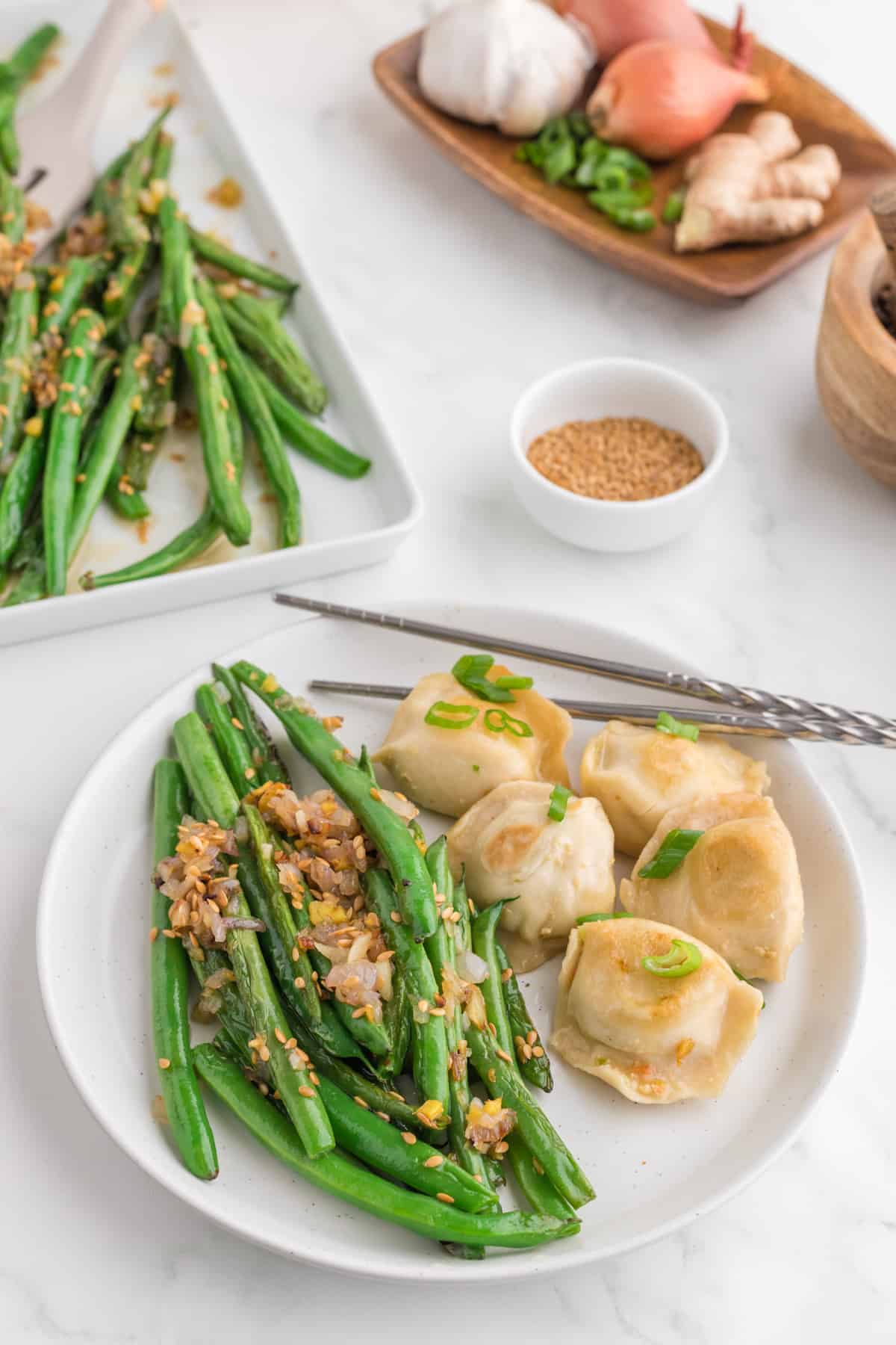 Chinese green beans serve in a white plate with dumplings.