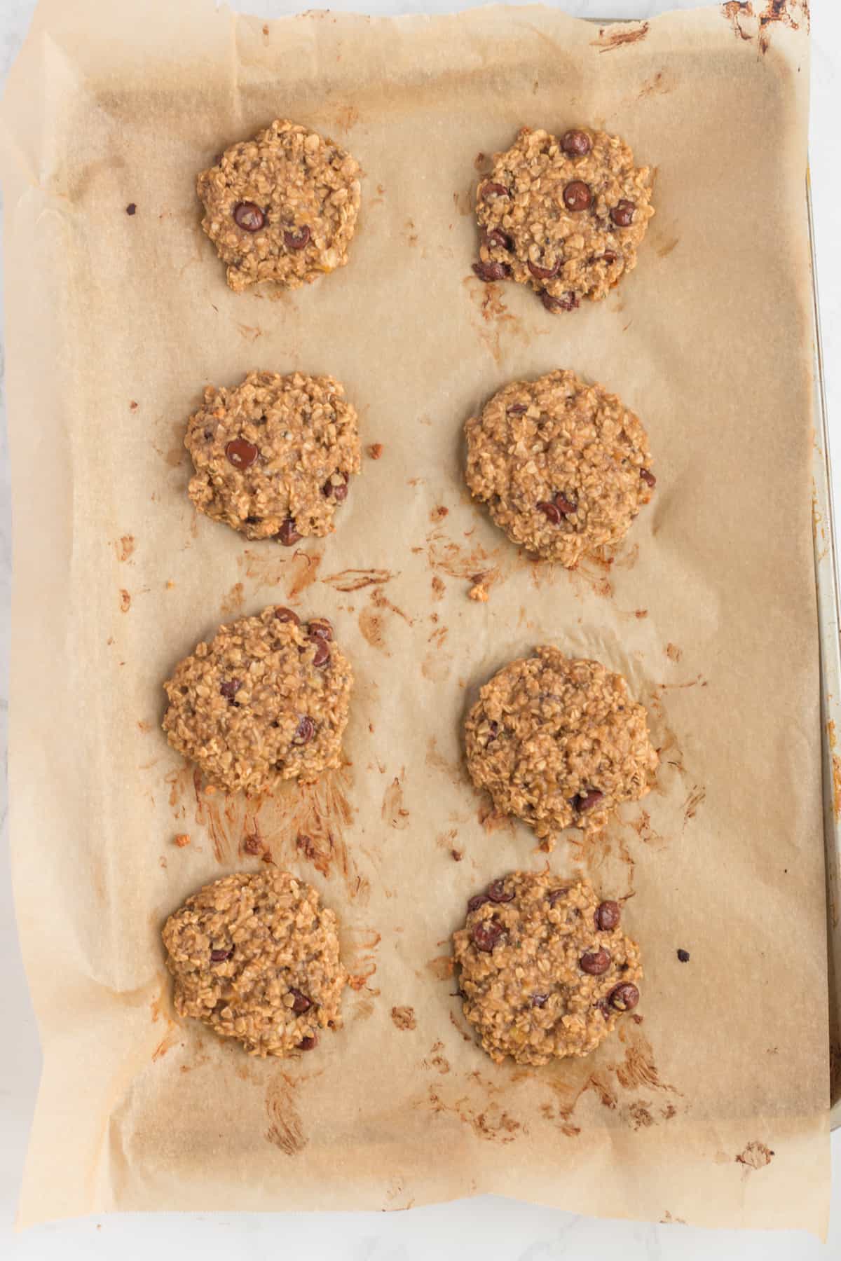 Eight cookies on a parchment-lined baking sheet.