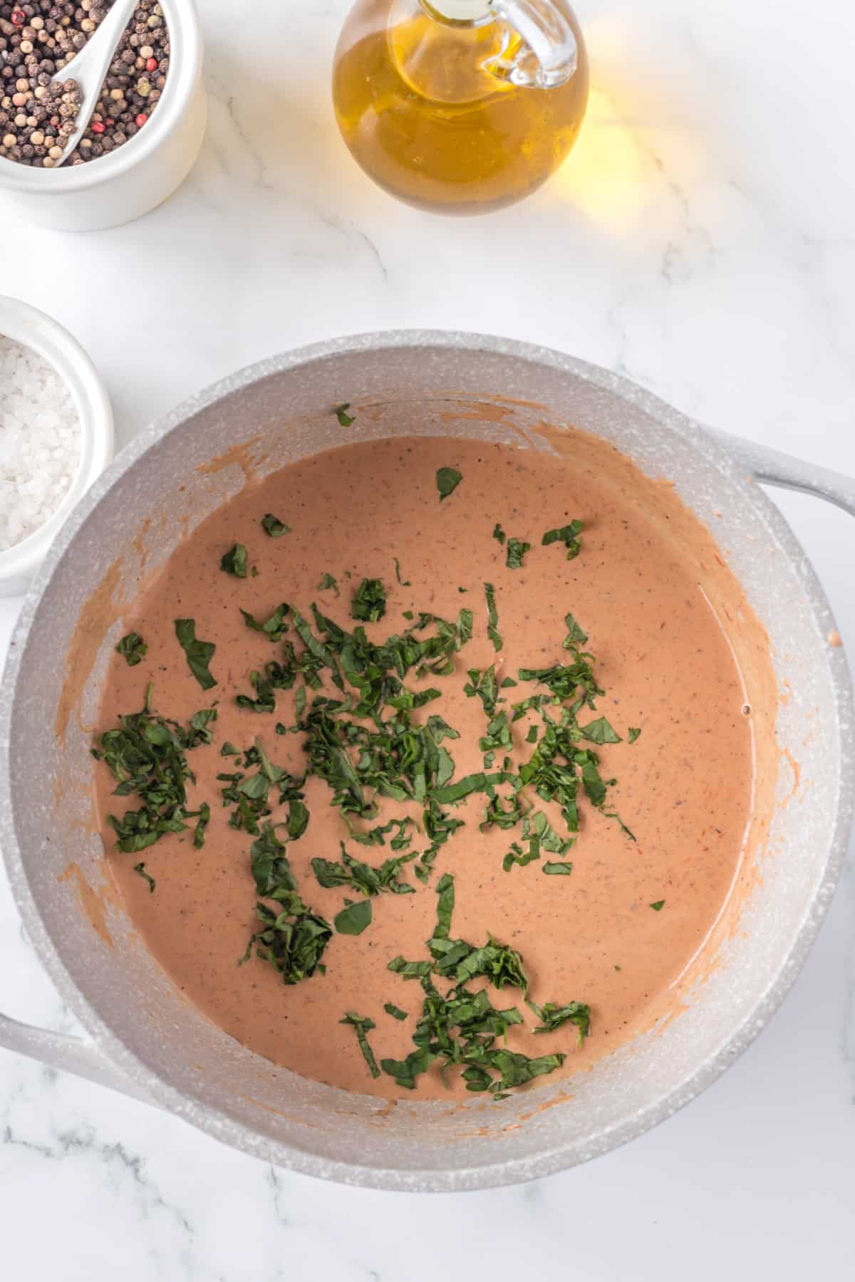 tomato soup in a large pot with chopped basil on top.