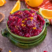 In a green bowl, with cranberry orange chipotle sauce takes center stage, with an orange background adding a pop of contrasting color.