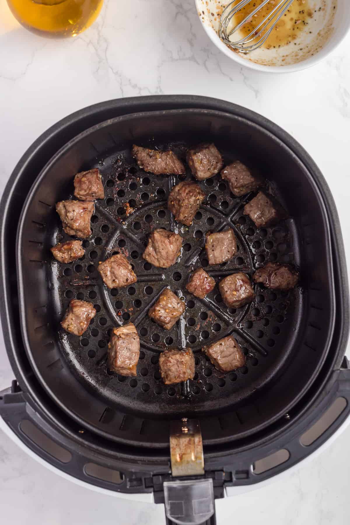 Steak in cubes cooked in the air fryer basket.