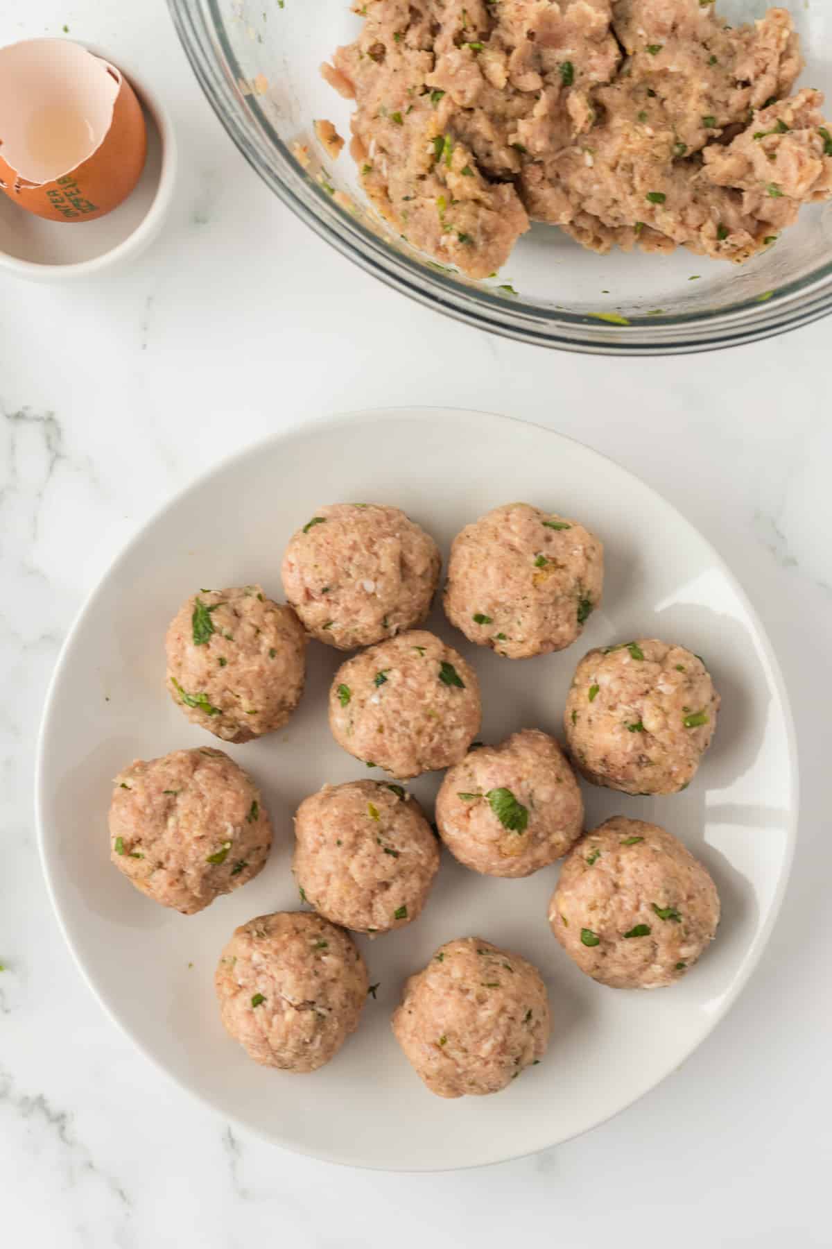 uncooked meatballs on a white plate.
