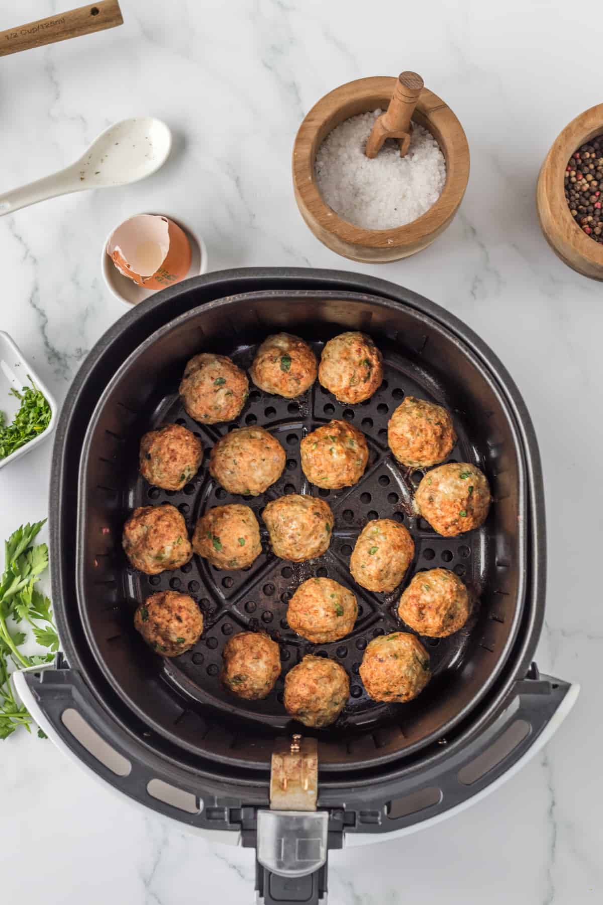 cooked meatballs in the basket of the air fryer