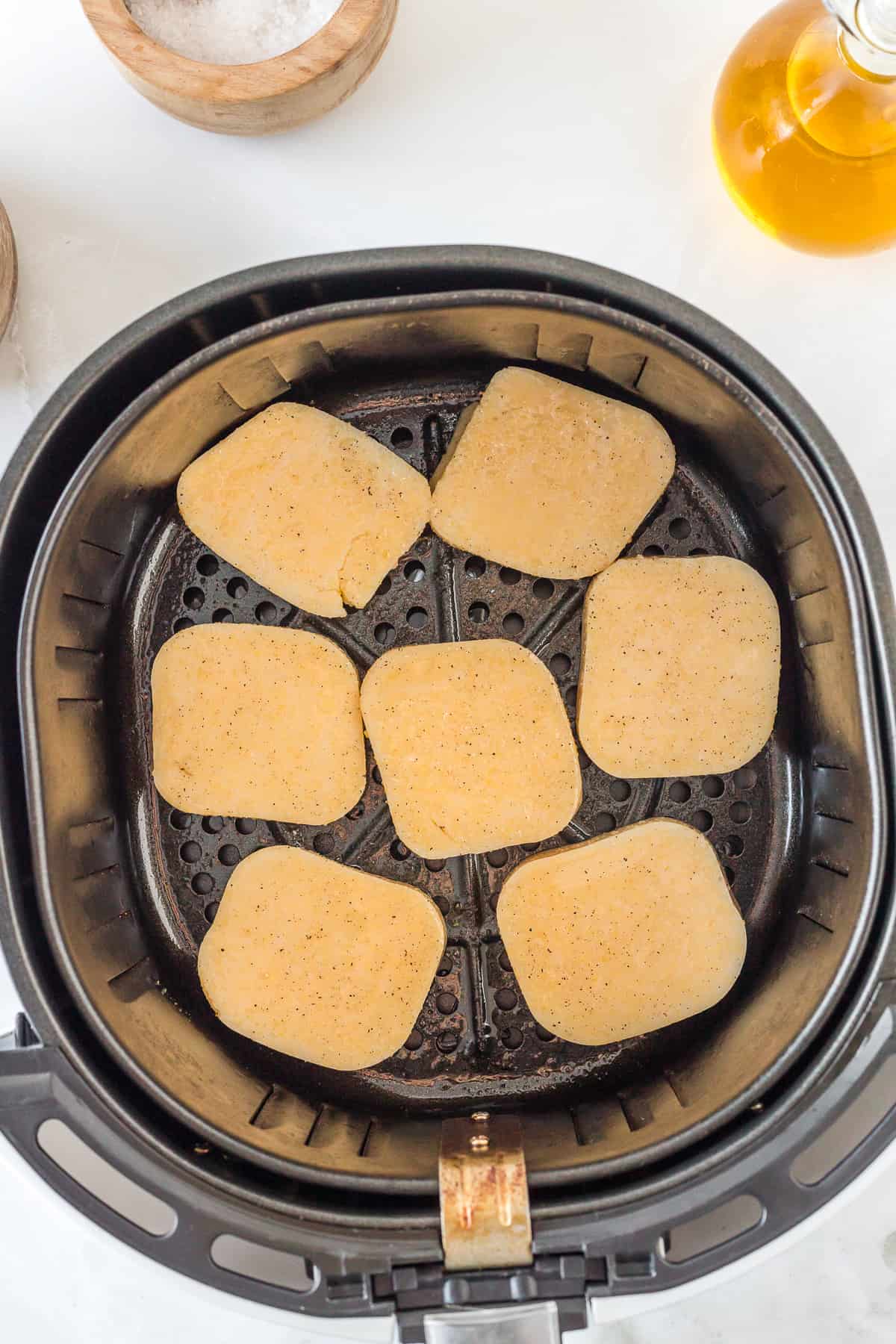 uncooked slices of polenta in the basket of the air fryer