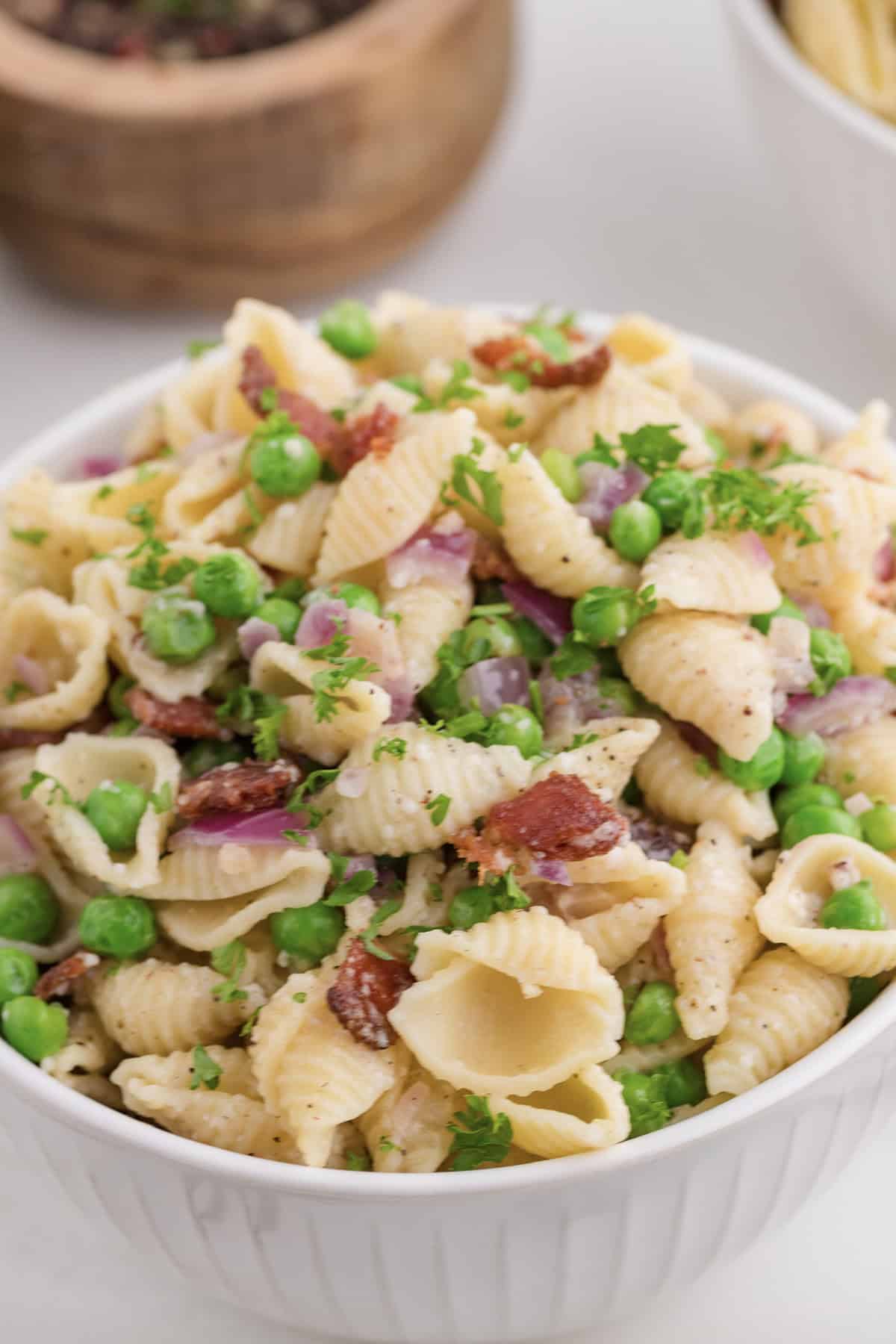 Pasta with peas serve in a white bowl.
