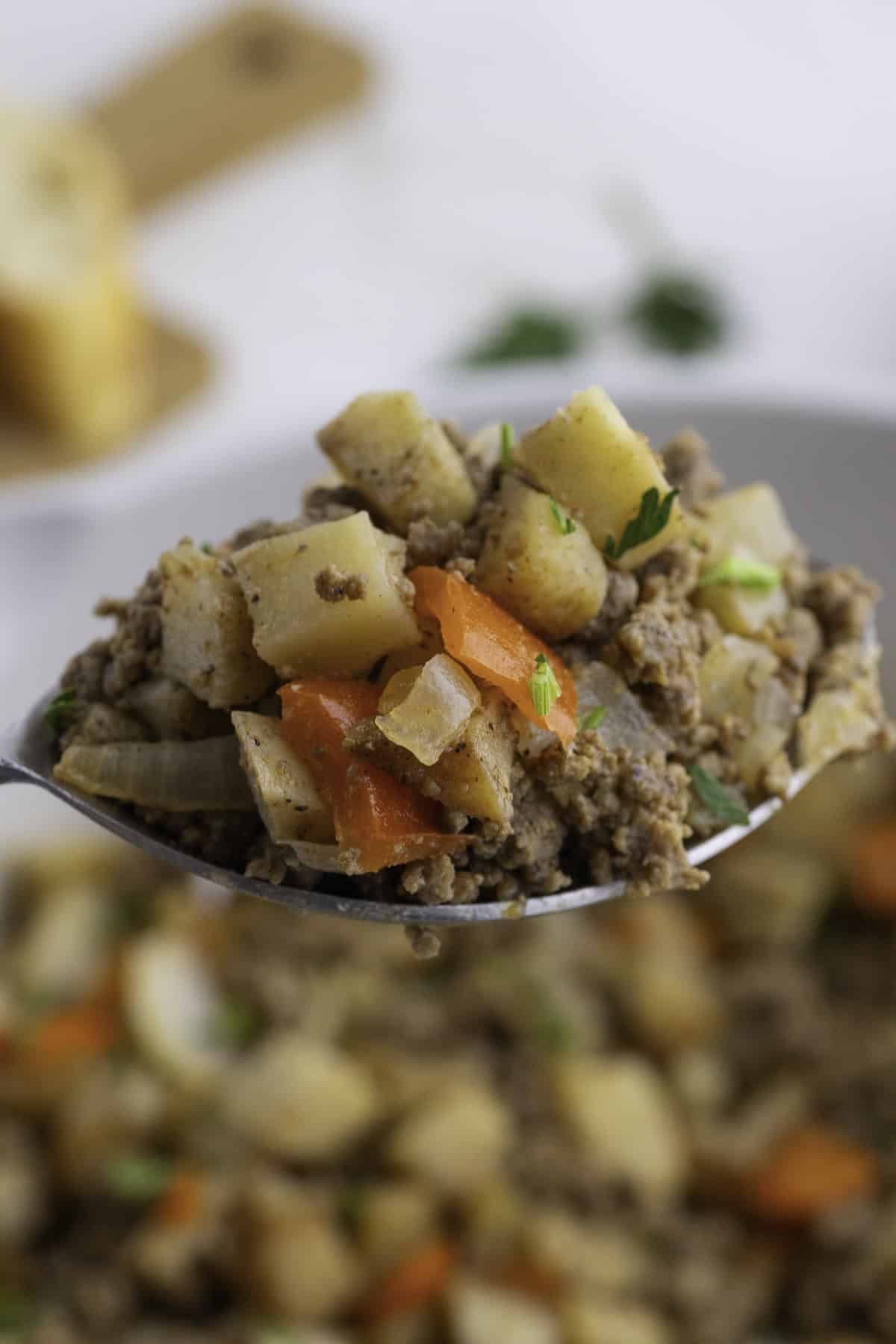 A spoonful of Tex-Mex ground beef mixed with diced potatoes, carrots, and onions creates a flavorful skillet dish.
