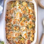 Casserole dish with Chicken,cheesy broccoli and potato casserole, topped with melted cheese and herbs.