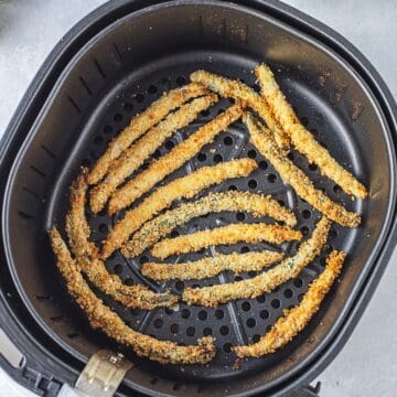 Air Fryer Green Bean Fries arranged in a single layer inside the basket, perfectly crisp and ready after cooking.