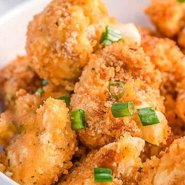 Close-up of crispy Air Fryer Bang Bang Cauliflower bites, garnished with chopped green onions.