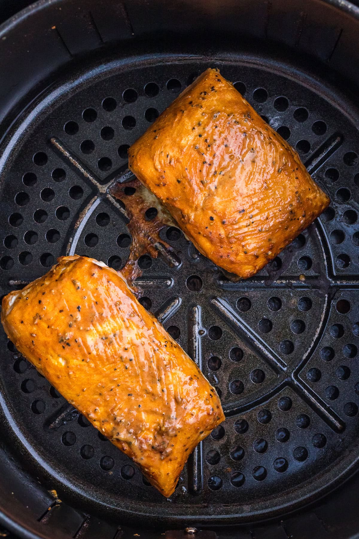 Deux filets de saumon assaisonnés sont présentés cuits dans un panier de friteuse.