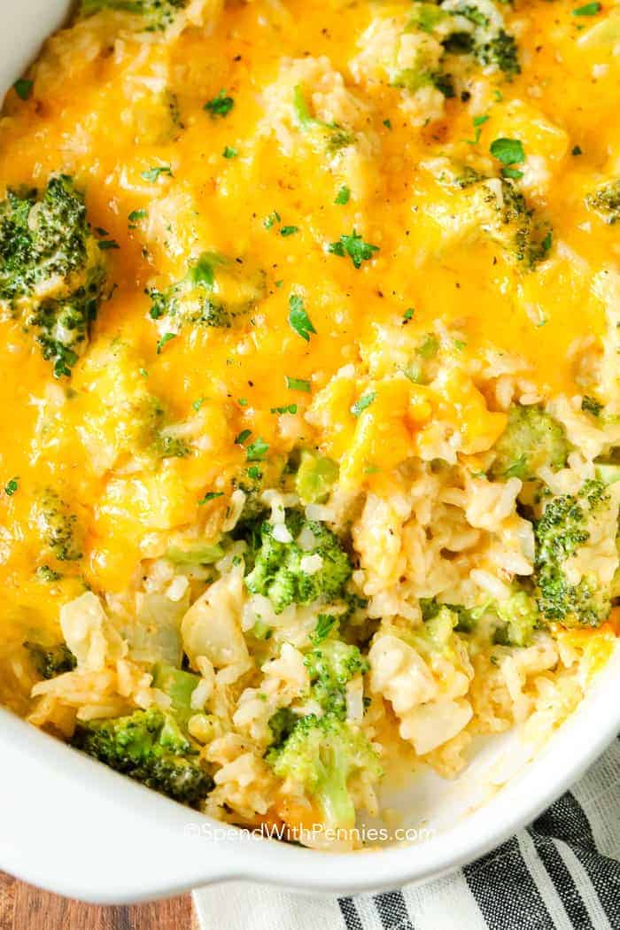 Close-up of a baked broccoli and rice casserole topped with melted cheddar cheese in a white dish.
