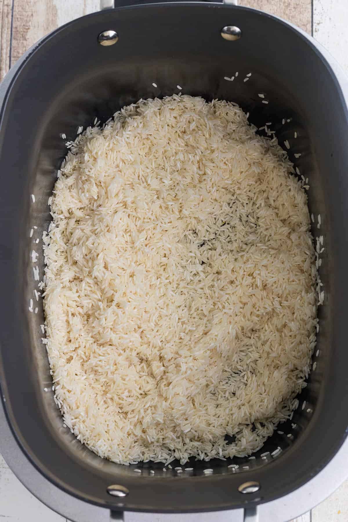 Uncooked basmati rice in the bowl of a ninja foodi possible cooker photographed from above.