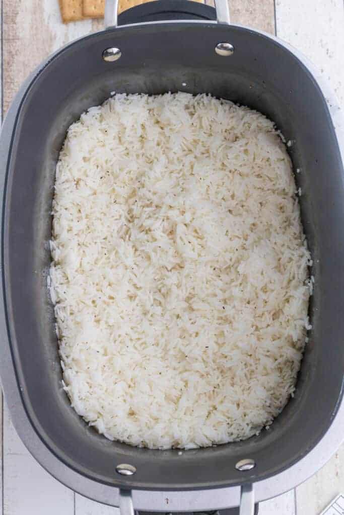 Cooked white rice in a Ninja foodi possible cooker, viewed from above, on a light wooden surface.