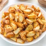 A white bowl filled with golden-brown, sesame-topped bread croutons, cut into bite-sized pieces.