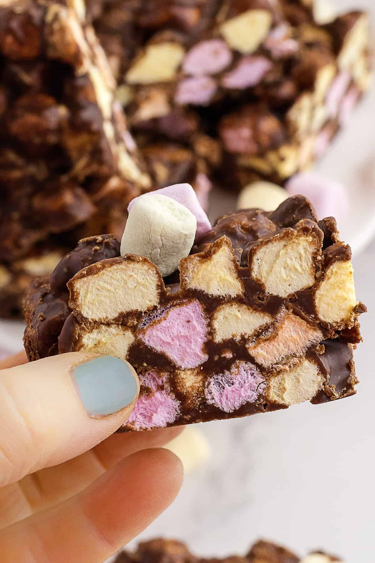 A hand holding a confetti squarer with colorful mini marshmallows visible inside.